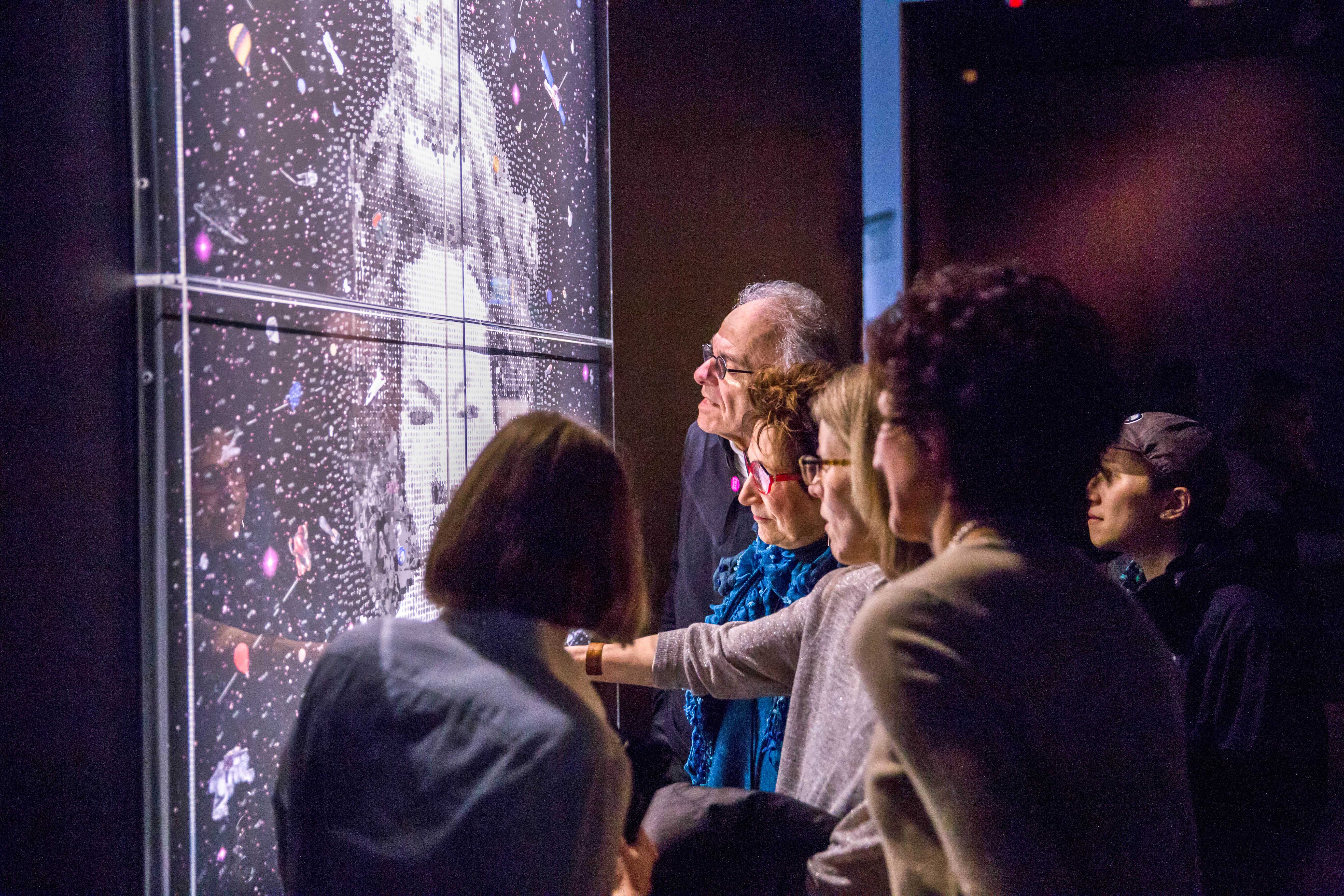 Visitors examine one of a series of collaged portraits at the exhibit.