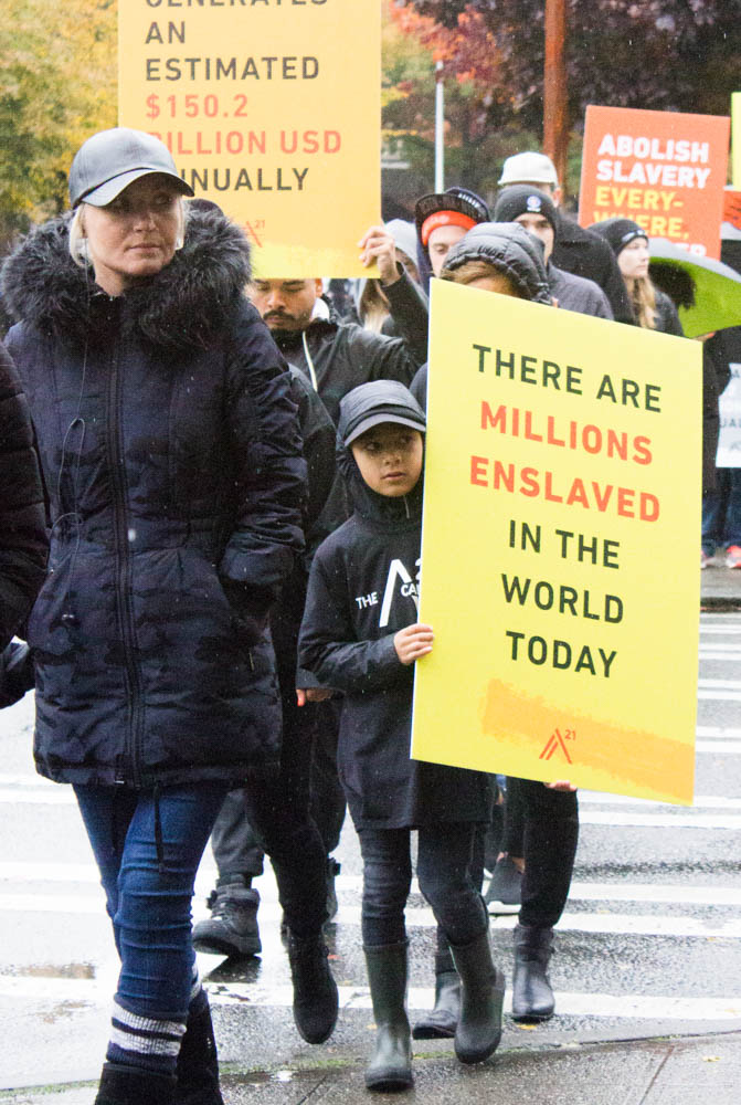 A child walks holding a large sign.