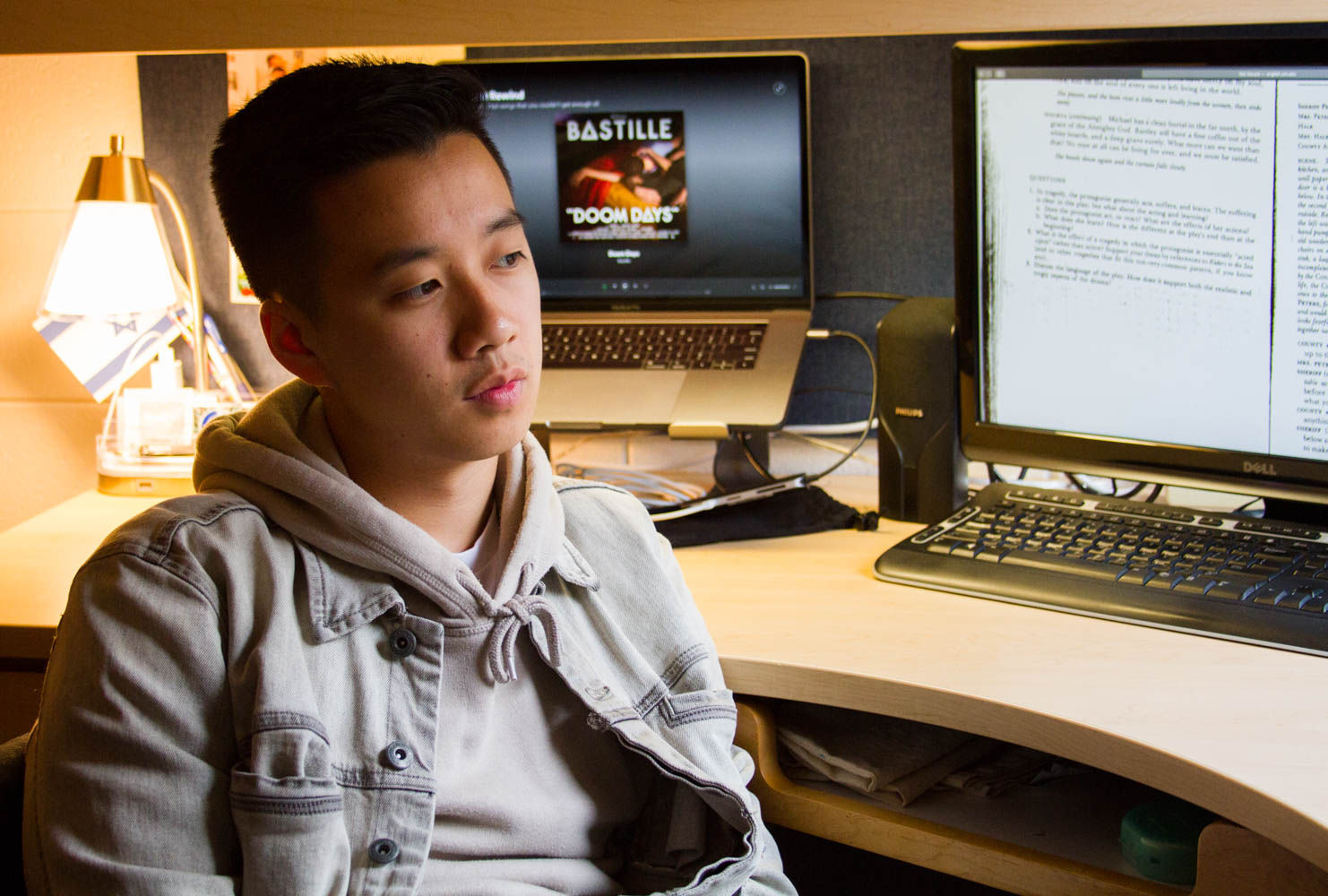 A portrait of a man in a dorm room looking out a window