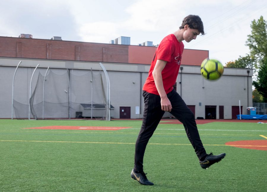 a man in a red shirt kicks a soccer ball into the air