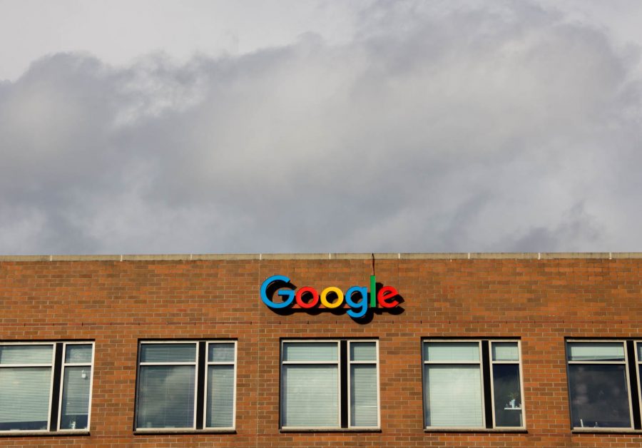 A brick building with the word Google on the front with grey clouds above it.