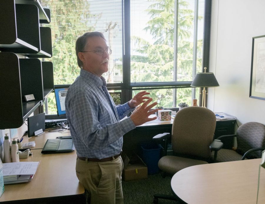 A man standing in an office speaking and gesturing with his hands