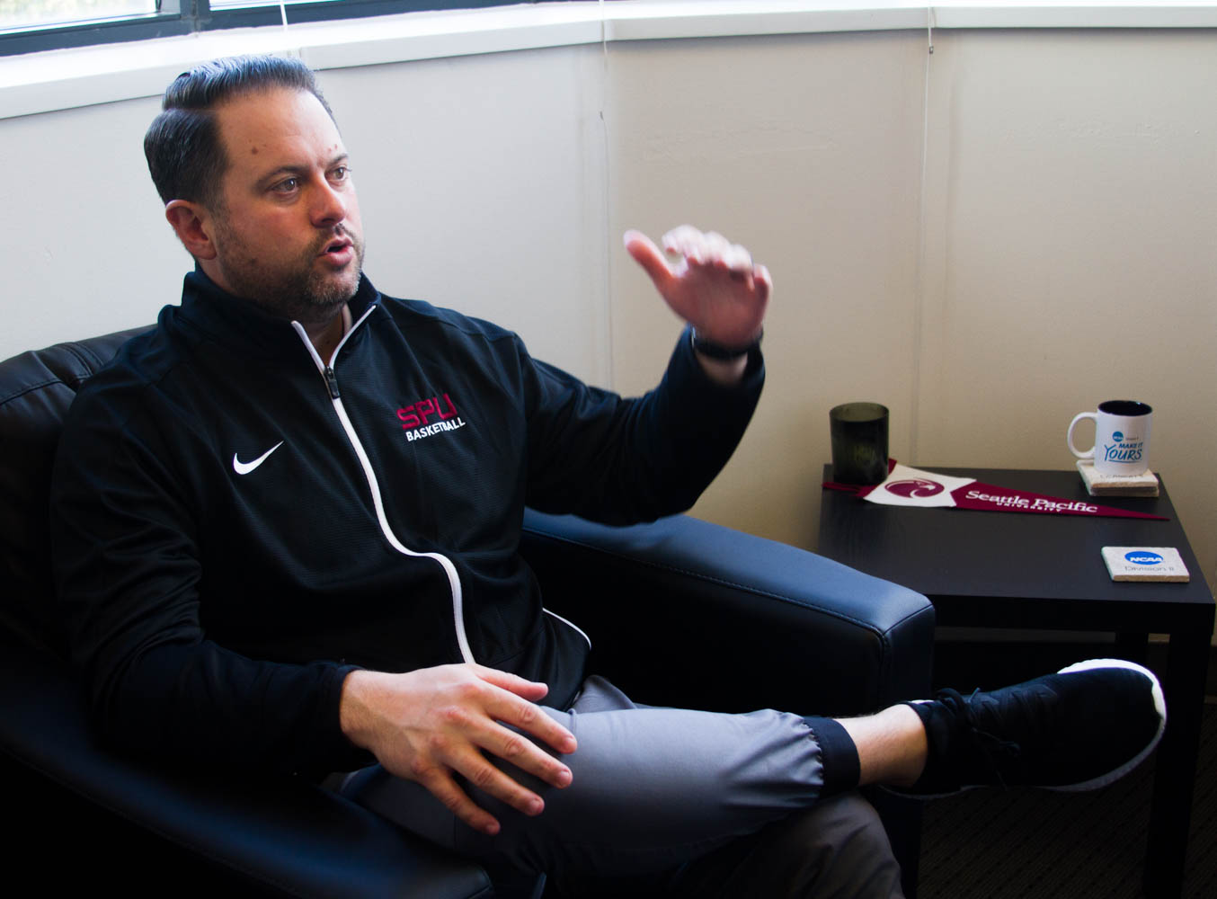 A man makes a hand gesture while sitting in a chair