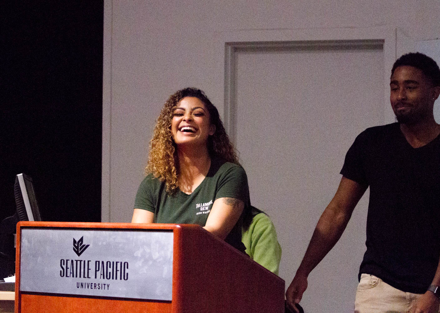 A woman standing behind a podium laughs