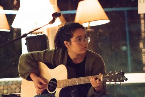 A woman strums a guitar