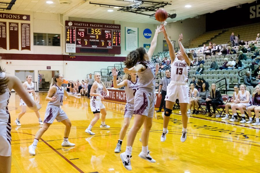 A woman shoots a basketball while defenders jump to block the shot