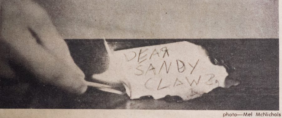 A man lights a match and burns a scrap of paper that reads Dear Sandy Claus