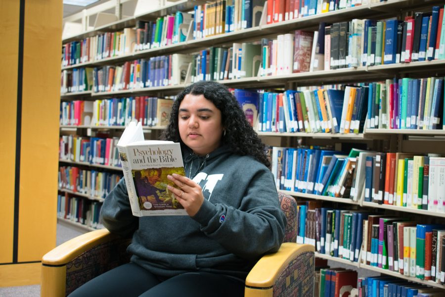 A woman sitting in a library reading a book
