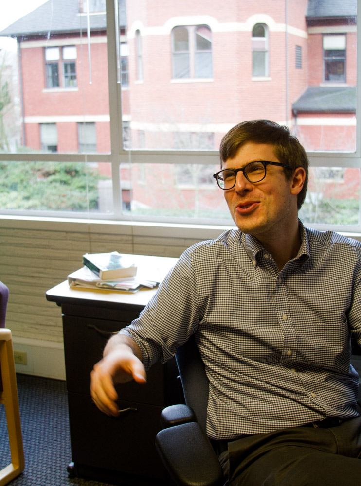 A man smiles while sitting in an office