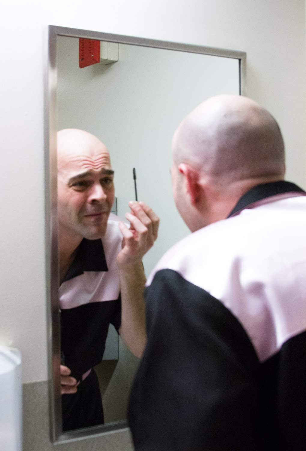 An Elvis tribute artist puts on makeup and prepares to put on a wig.