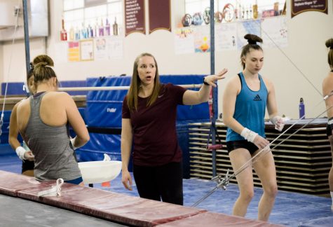 A female gymnastics coach points while talking to gymnasts