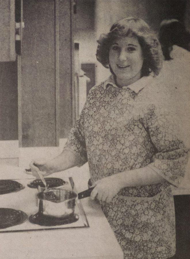 a woman stands behind a stove cooking