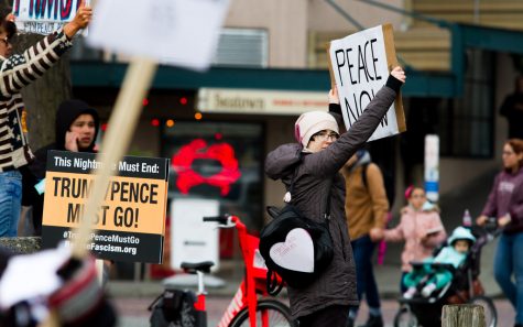 A woman holds up a sign that reads "peace now"