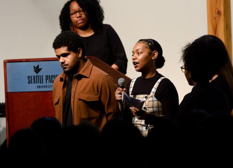 a woman holds a microphone and speaks to a crowd