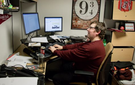 A man smiles while sitting behind a desk
