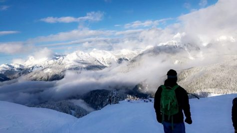 a man stands with snowy mountains in the background