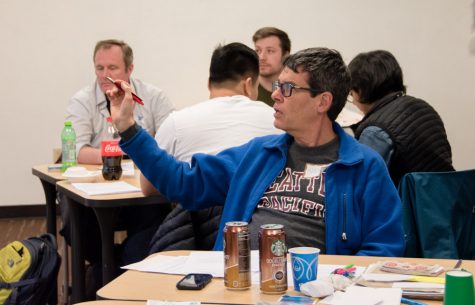 A man points and asks a question in a classroom