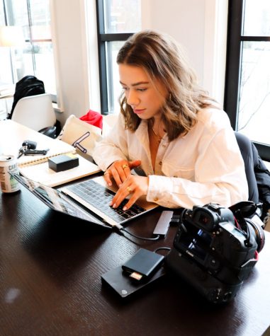 A woman works on a computer with a camera next to her