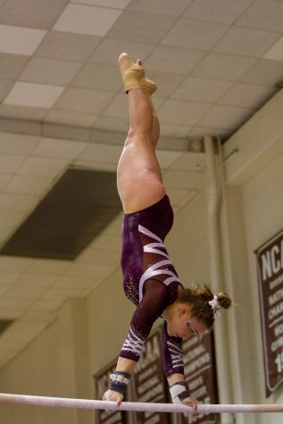 A woman holds on to a bar and swings while upside down