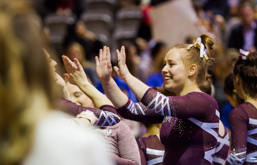 a gymnast gives a high five to her teammates