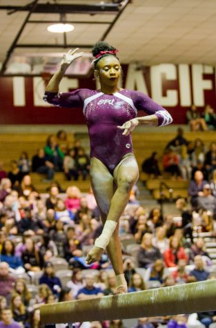 a gymnast stands and poses on a balance beam