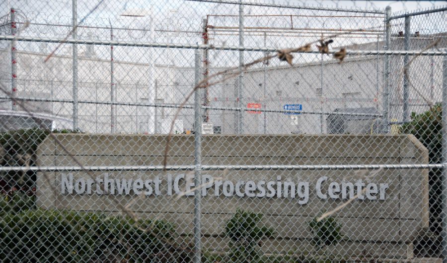 a photos of a sign that reads Northwest ICE Processing Center with a chain link fence in front of it