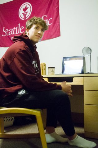 a male student sits at a desk in a dorm