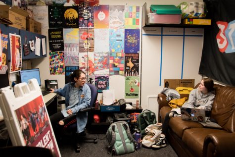 two women talk in an office with colorful posters on the walls