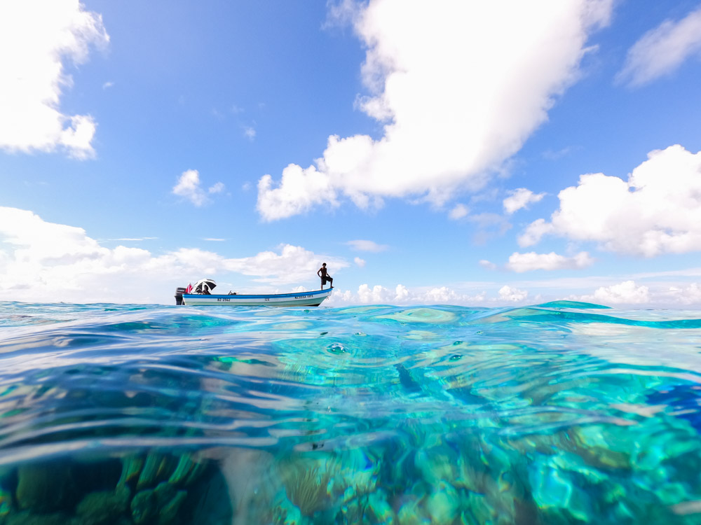 a man stands on a boat over a reef