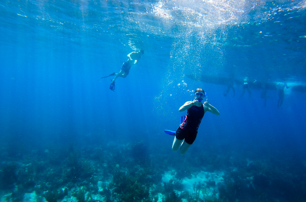 a woman gives a "thumbs up" while snorkelling