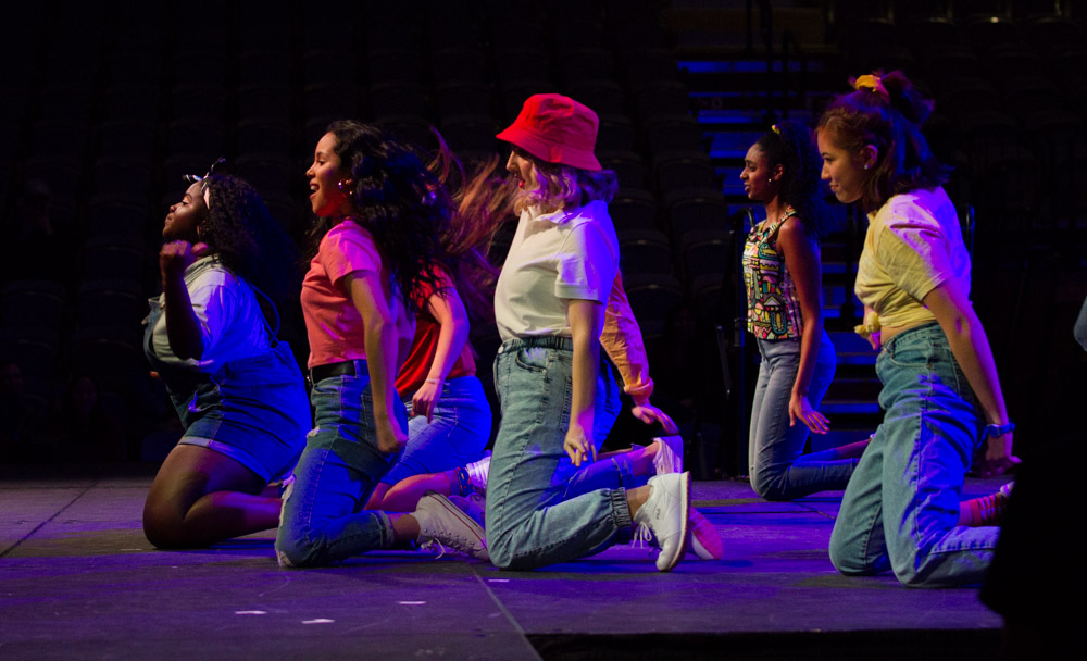 A group of dancers kneel on the stage during a performance