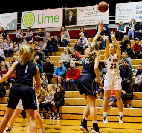 a woman shoots a basketball with defenders in front of her