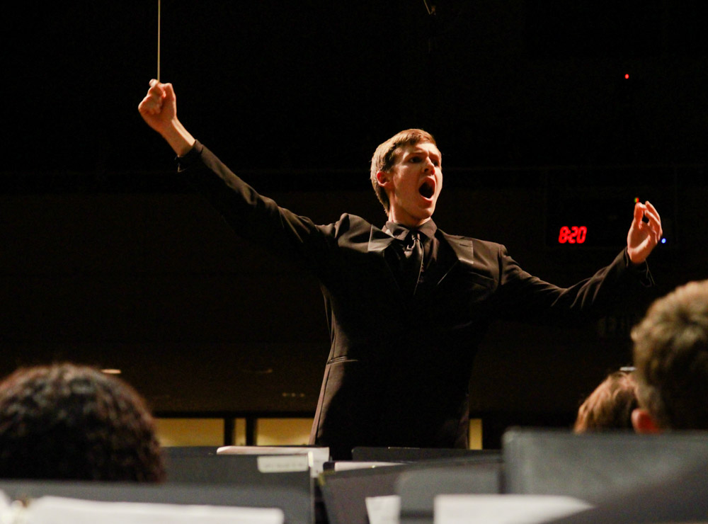a conductor stands and motions while directing a band