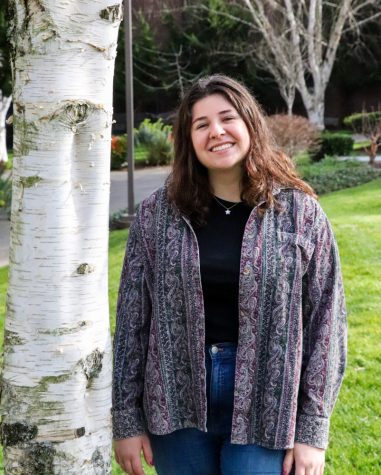 a woman stands by a tree and poses for a photo