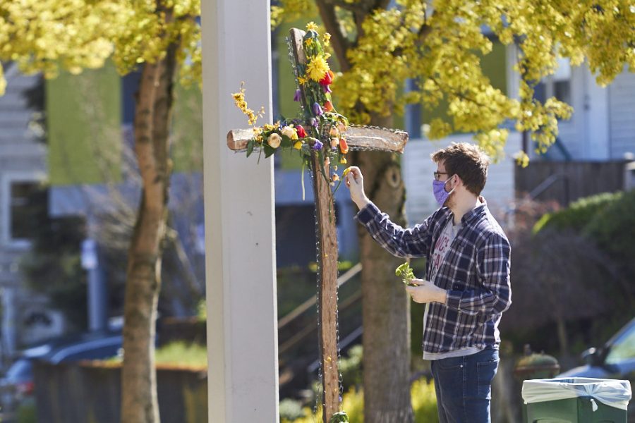 A man removes flowers decorating a cross outside of a church