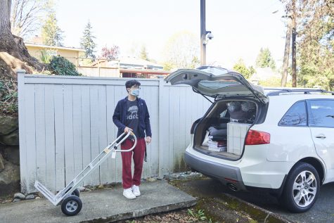 a man stands behind a car with a hand truck