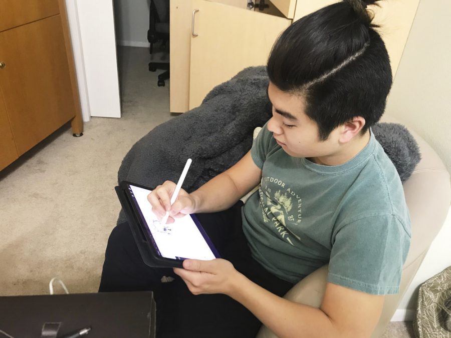 A man sits and draws on a tablet