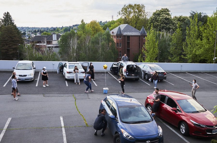 a group of people stand at a distance in a parking lot and celebrate their friends birthday