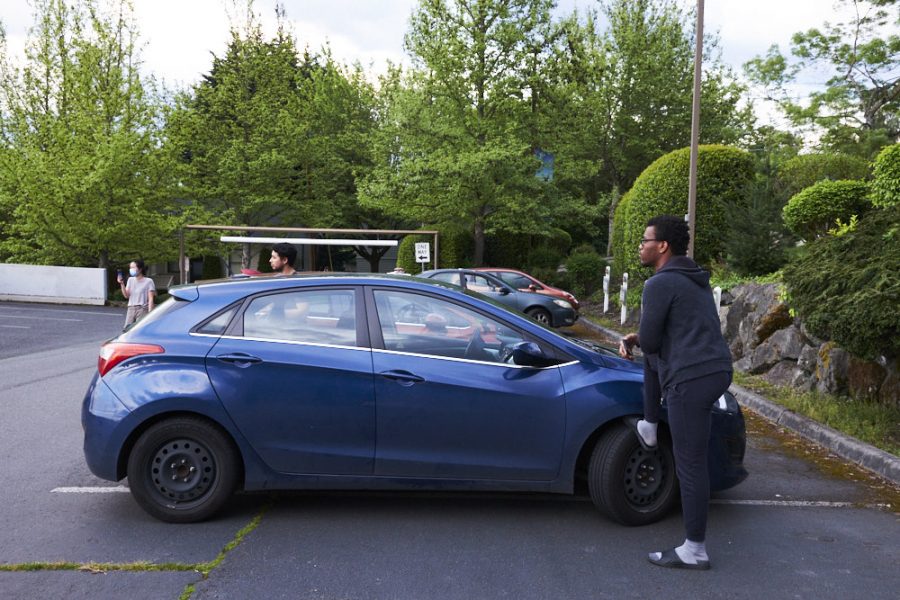 a man leans against a car in a parking lot