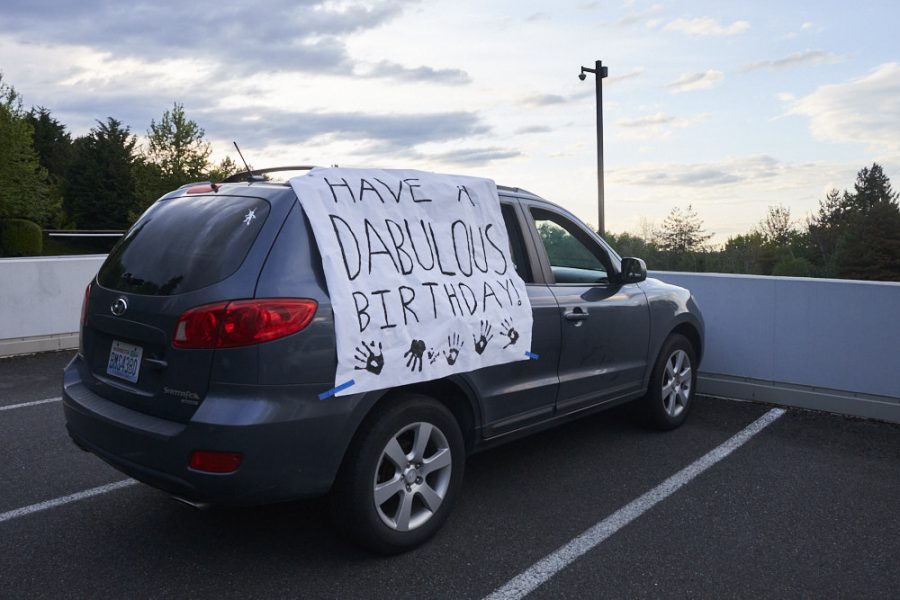 a banner reading have a dabuolous birthday is draped across a parked car