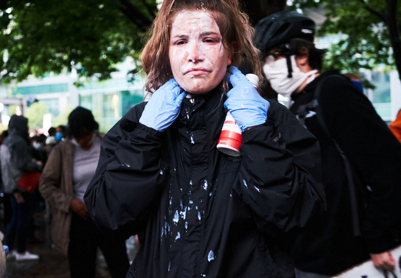 a woman dumps milk on her face after being pepper sprayed