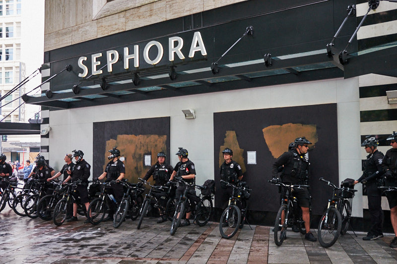 Police on bicycles line up in front of a sephora store