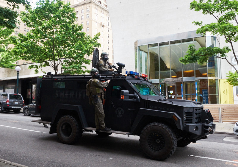 two police officers ride on an armored vehicle