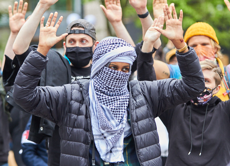 a woman holds her hands up during a protest