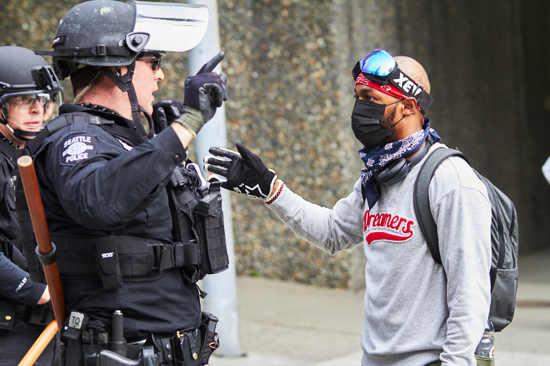 A man speaks to police in riot gear