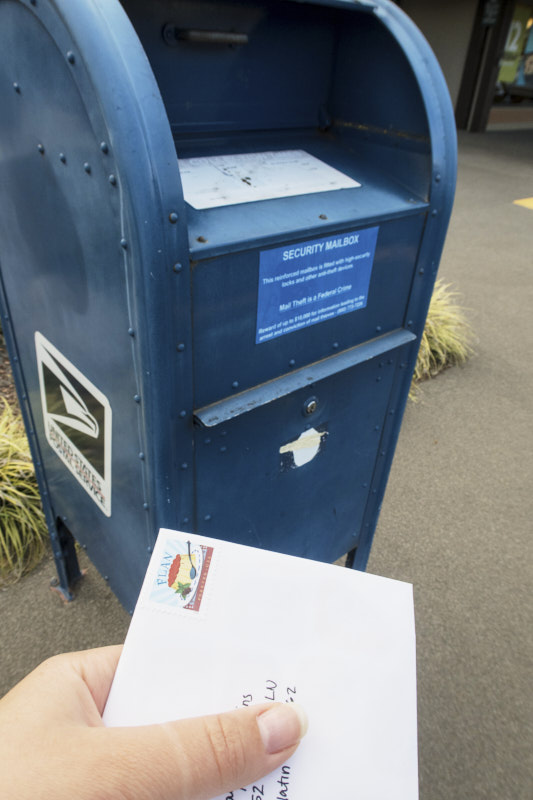 a letter being dropped in a postal service box