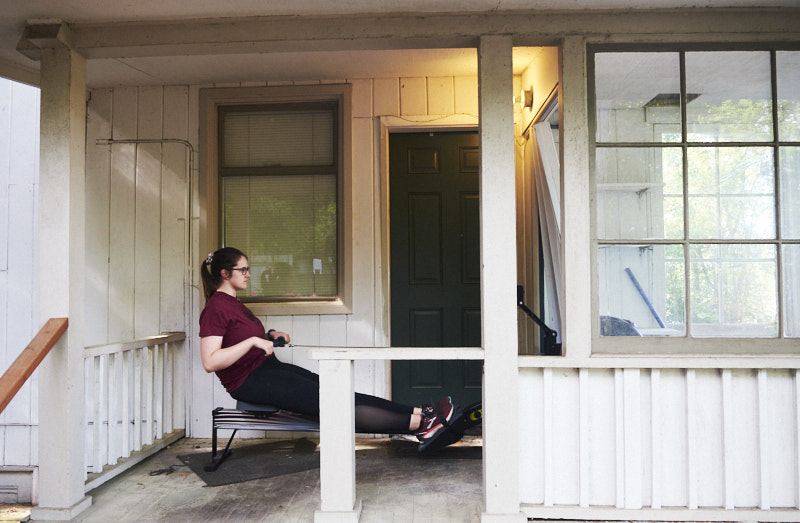 a woman works out on a rowing machine on a porch