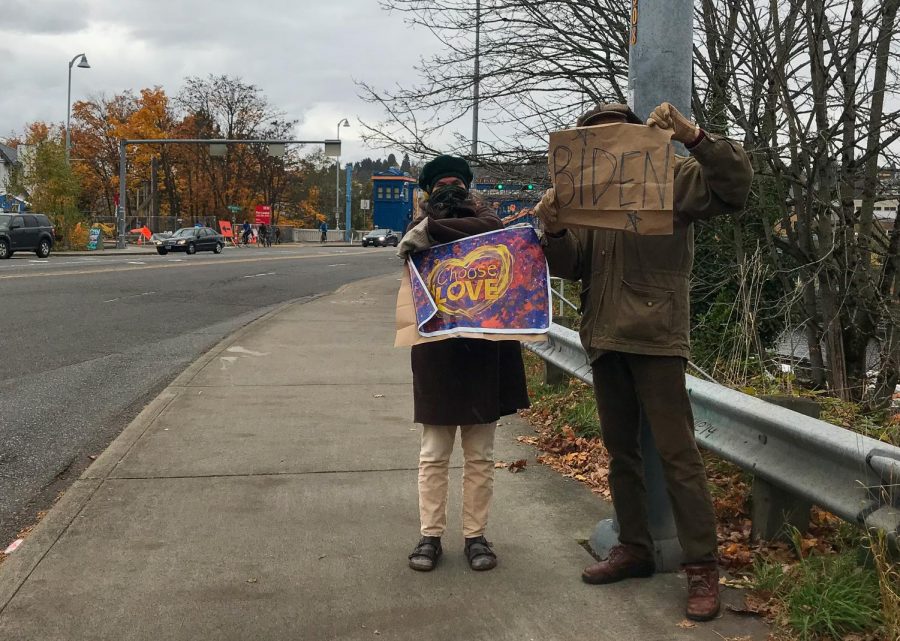 A couple hold signs while celebrating Bidens victory. As cars passed by they encouraged them to honk in support.