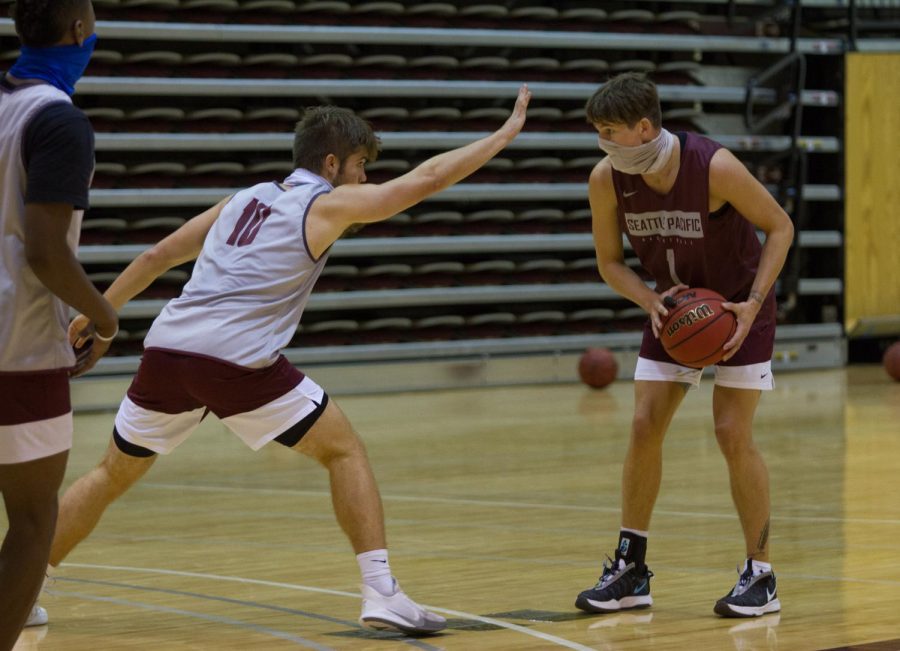 Zack Paulson, sophmore guard, practices one on one against freshman Chris Penner. Basketball games will resume for a shorted season in January.