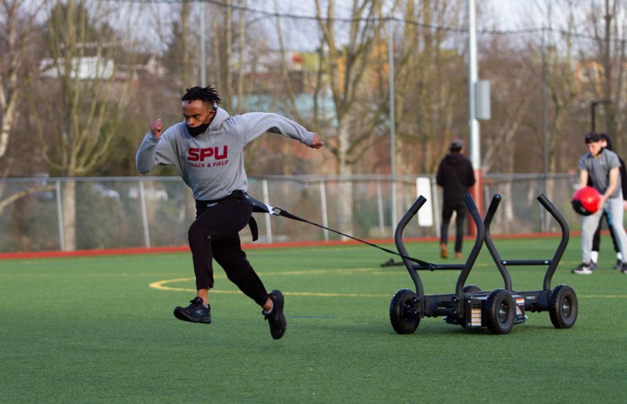 Male athlete runs while pulling a weighted sled